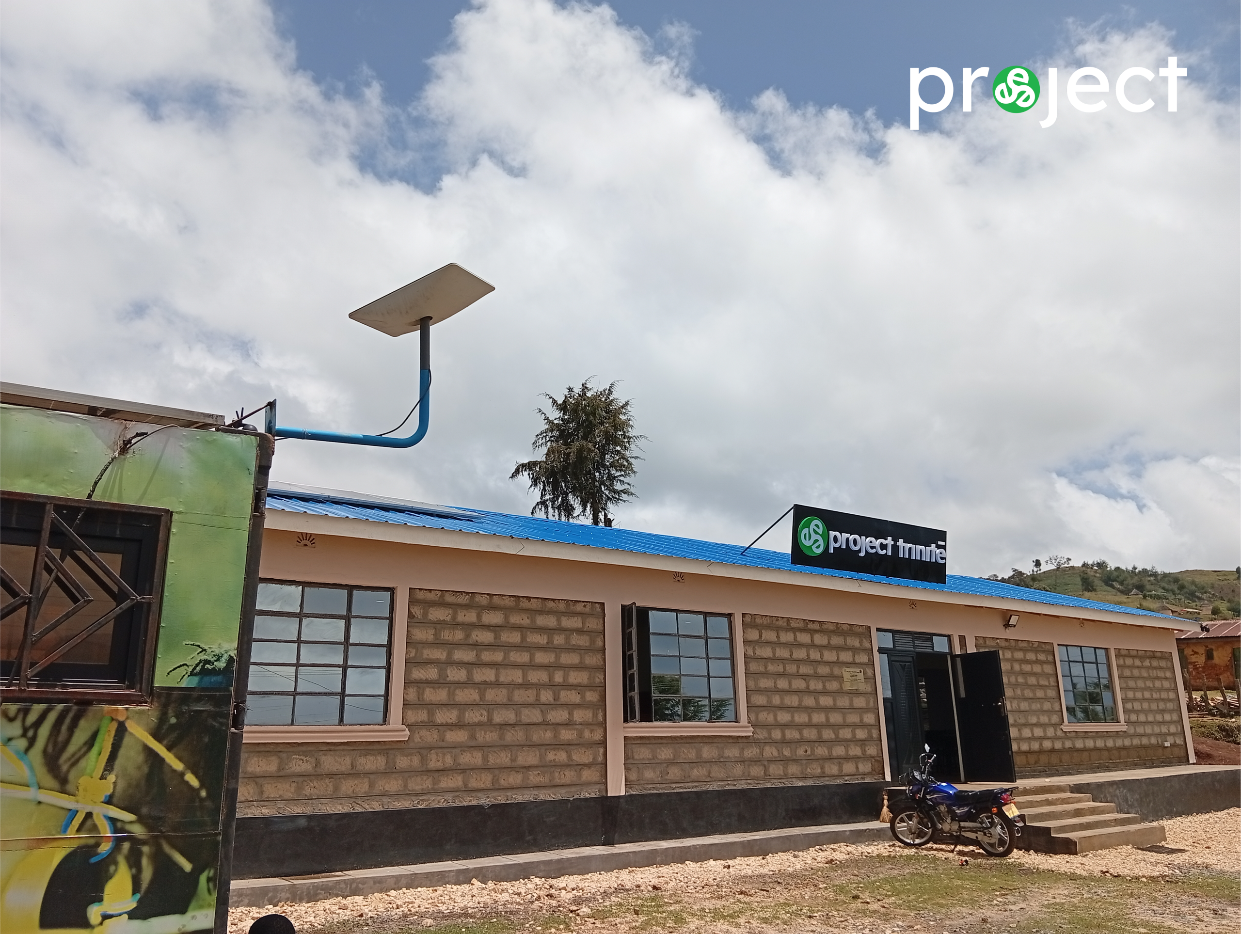Front view of the David Connor Trinitech Center in rural Kenya with branded signage and a satellite dish providing high-speed internet connectivity.