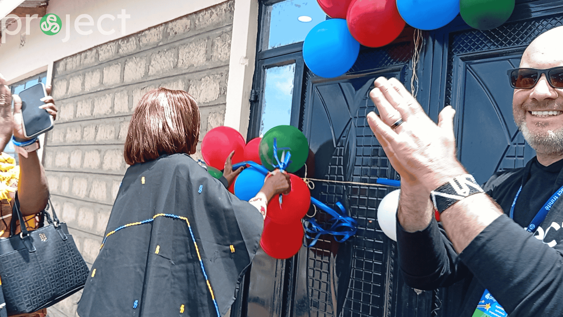 Community leader cuts a ribbon surrounded by balloons at the grand opening of the David Connor Trinitech Center, while guests applaud.